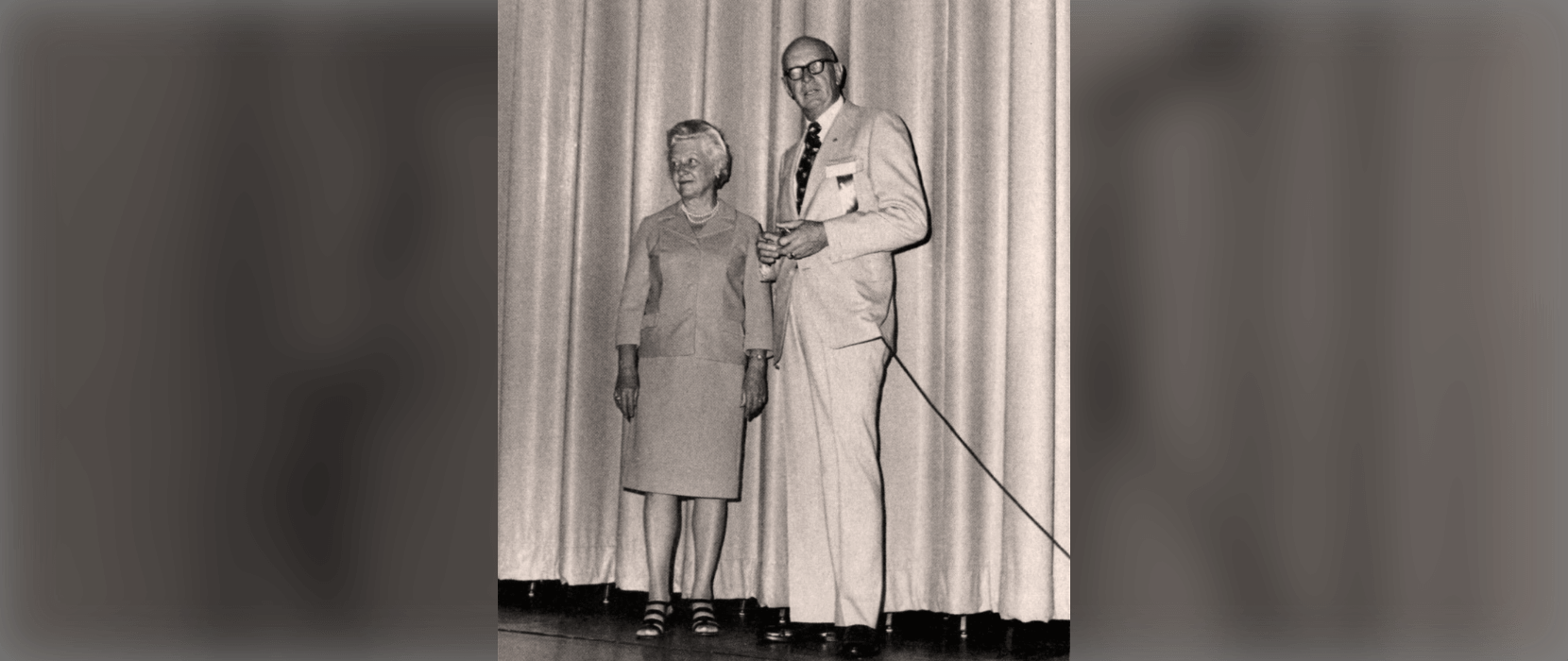 Black and white photo of a woman and man standing on a stage