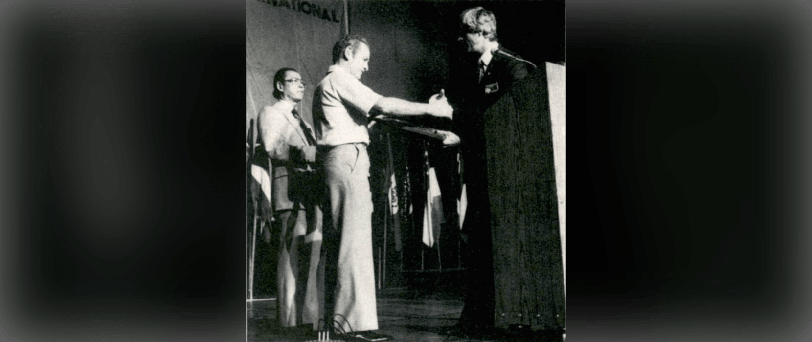 Black and white photo of a man accepting an award from another man