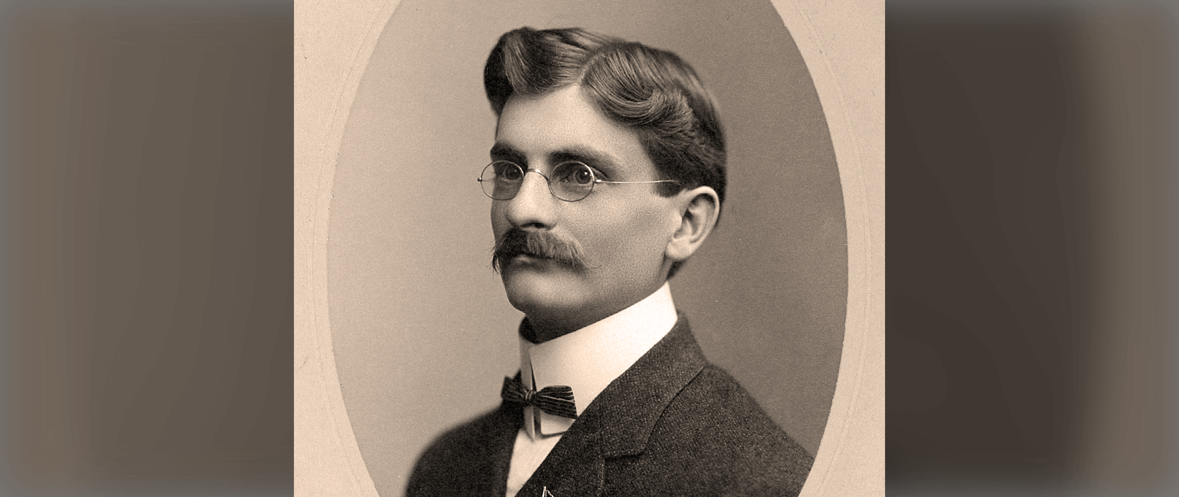 Sepia tone image of man with a mustache and glasses