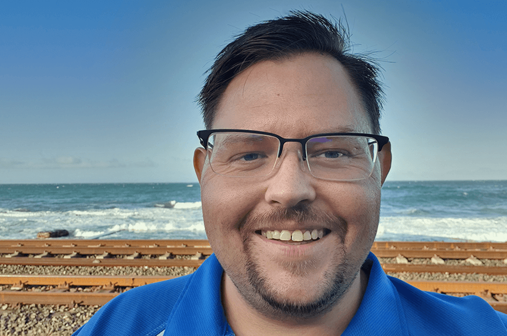 “Man in glasses and blue shirt standing near ocean”
