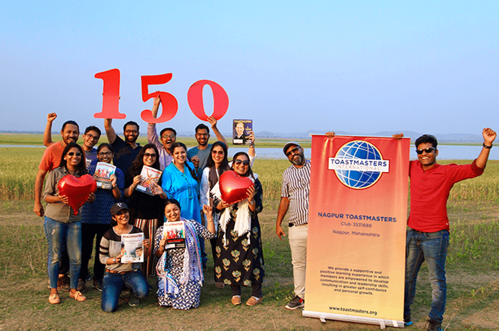 Group of people posing outdoors with banner and cut out numbers 150