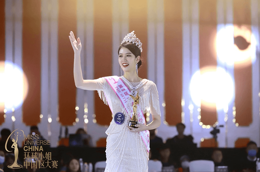 Woman wearing crown and waving onstage