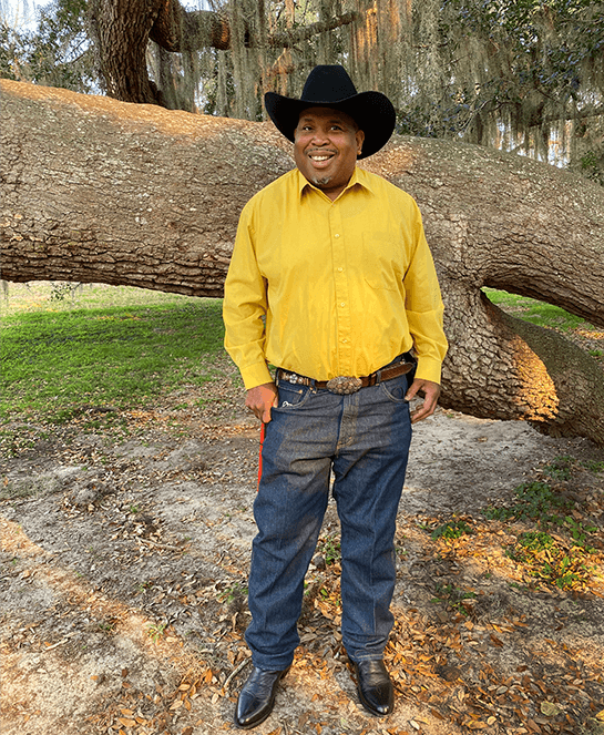 Man posing outdoors in yellow shirt and hat
