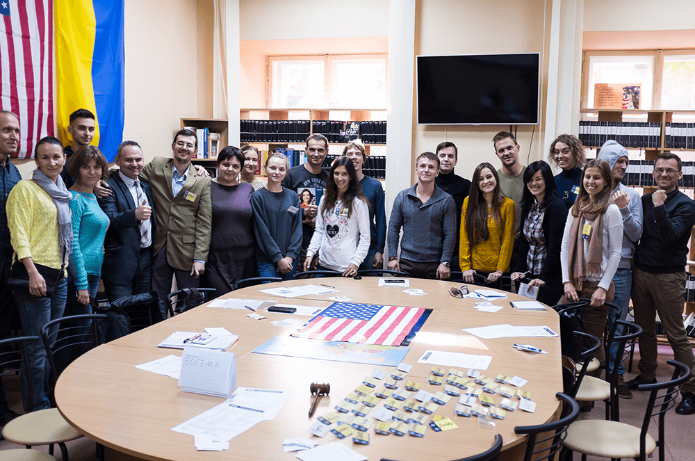 Group of people posing indoors near Ukrainian and American flags
