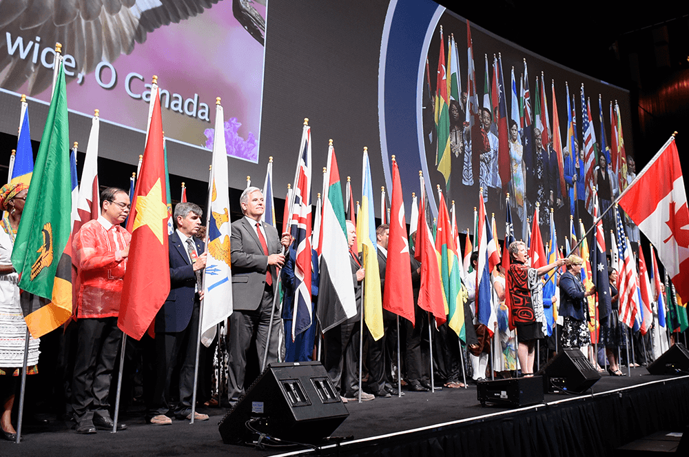 People standing in line onstage holding flags representing their country