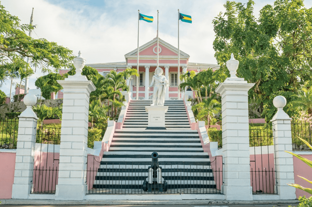 Government House with white pillars and large staircase leading to pink building