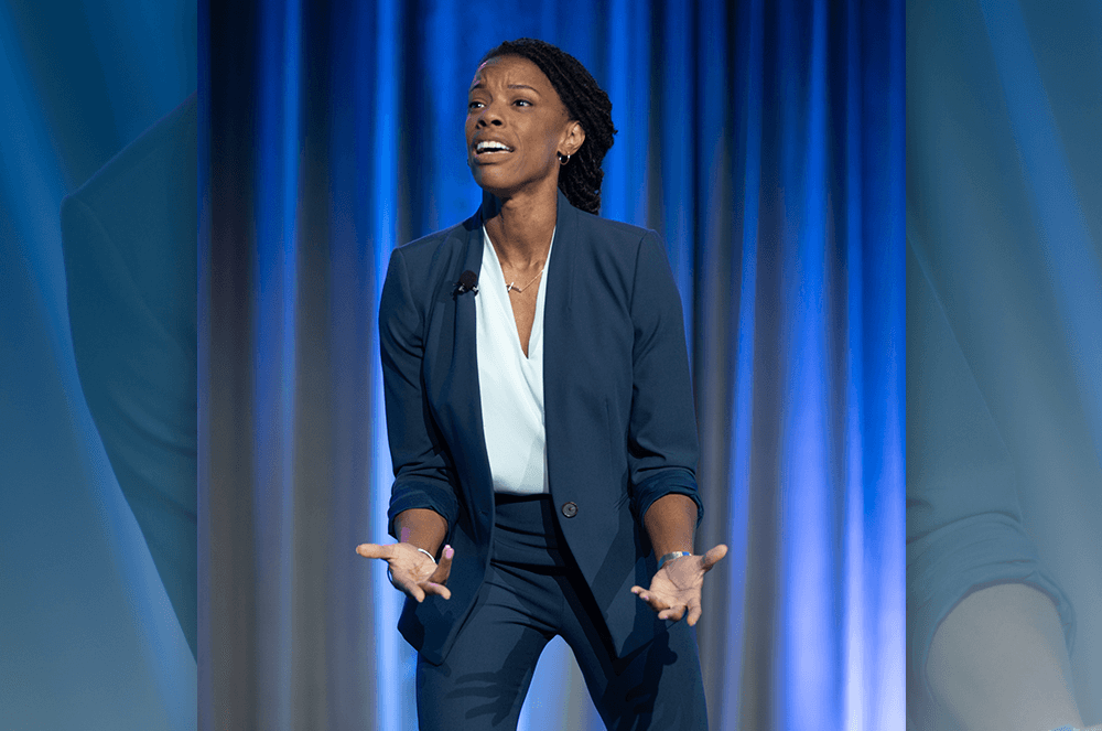 Woman in dark blue suit using hand gestures and facial expressions onstage