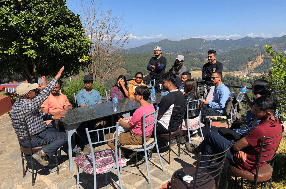 Group of tourists gathered outdoors with mountain range in background